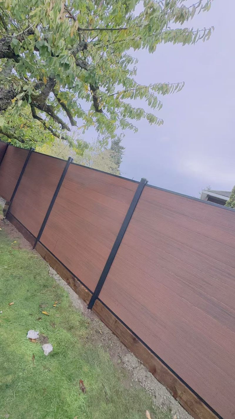 Walnut composite fence with black posts beside an autumn garden path